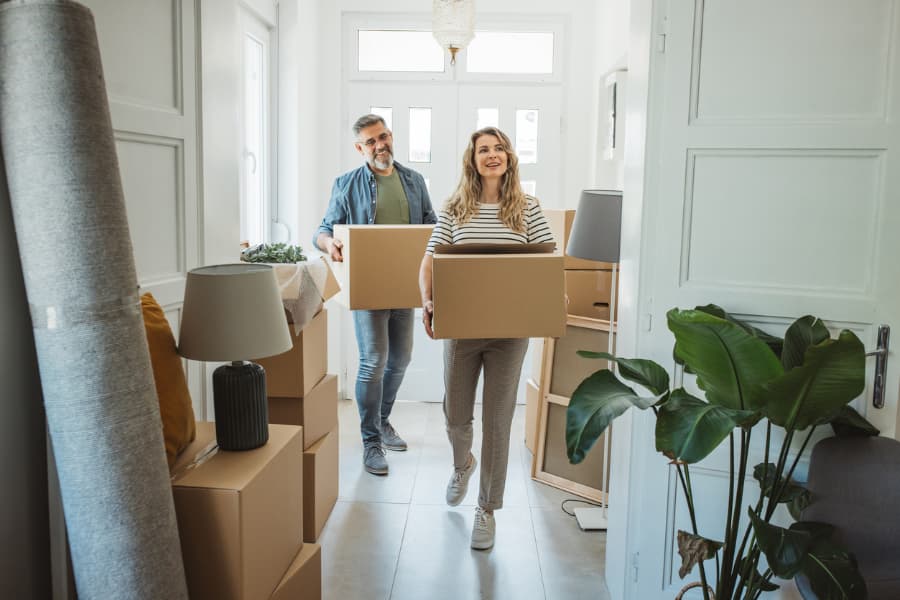Homeowners carrying boxes to move into larger home with more space
